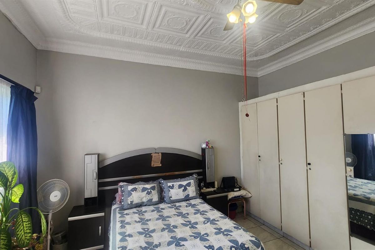 A bedroom featuring a decorative pressed metal ceiling, built-in wardrobes, and tiled flooring.