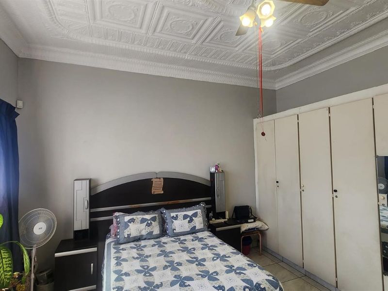 A bedroom featuring a decorative pressed metal ceiling, built-in wardrobes, and tiled flooring.