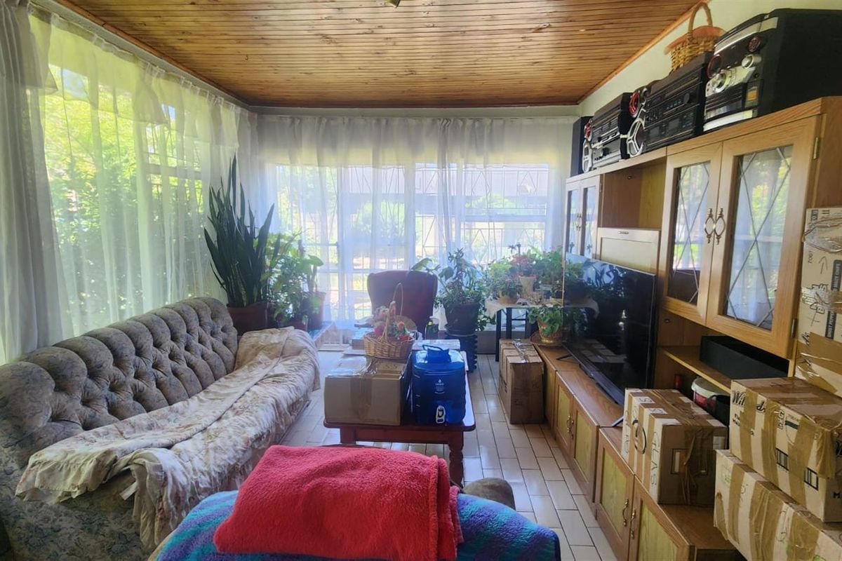 A sunroom or living area featuring a timber-clad ceiling, large windows with natural light, and tiled flooring.