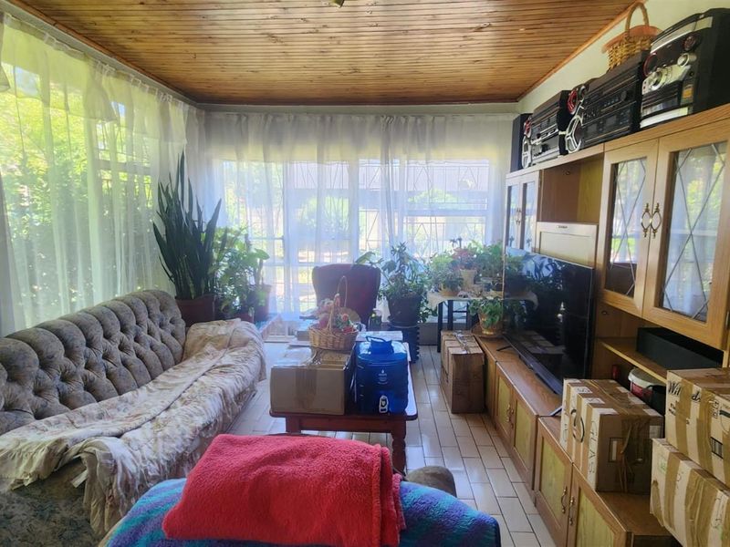 A sunroom or living area featuring a timber-clad ceiling, large windows with natural light, and tiled flooring.