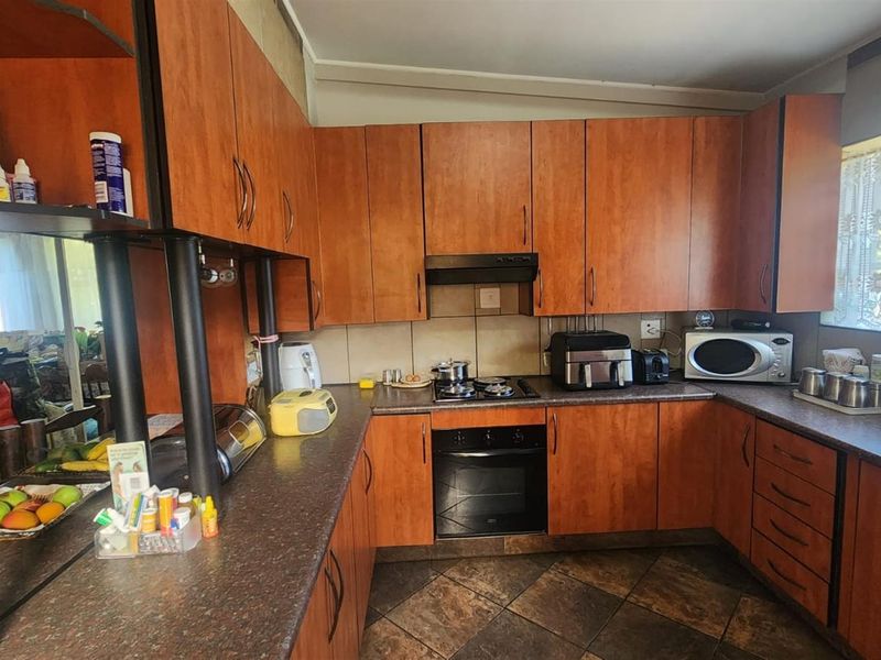 A functional kitchen featuring wood-look cabinetry, dark laminate countertops, a built-in oven, gas hob, and tiled flooring.