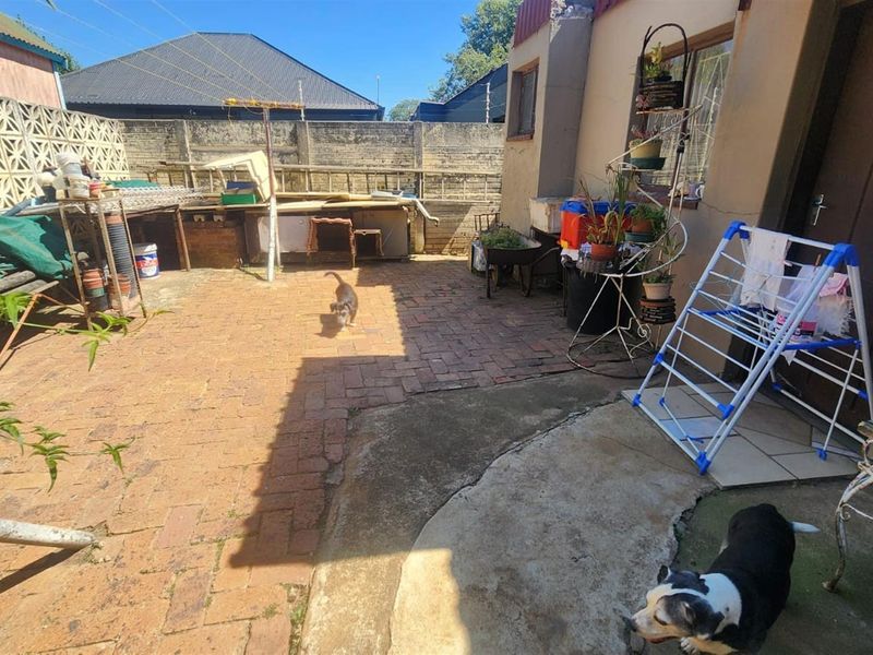 A rear courtyard area featuring brick and concrete paving, enclosed by a high boundary wall with decorative breeze blocks.