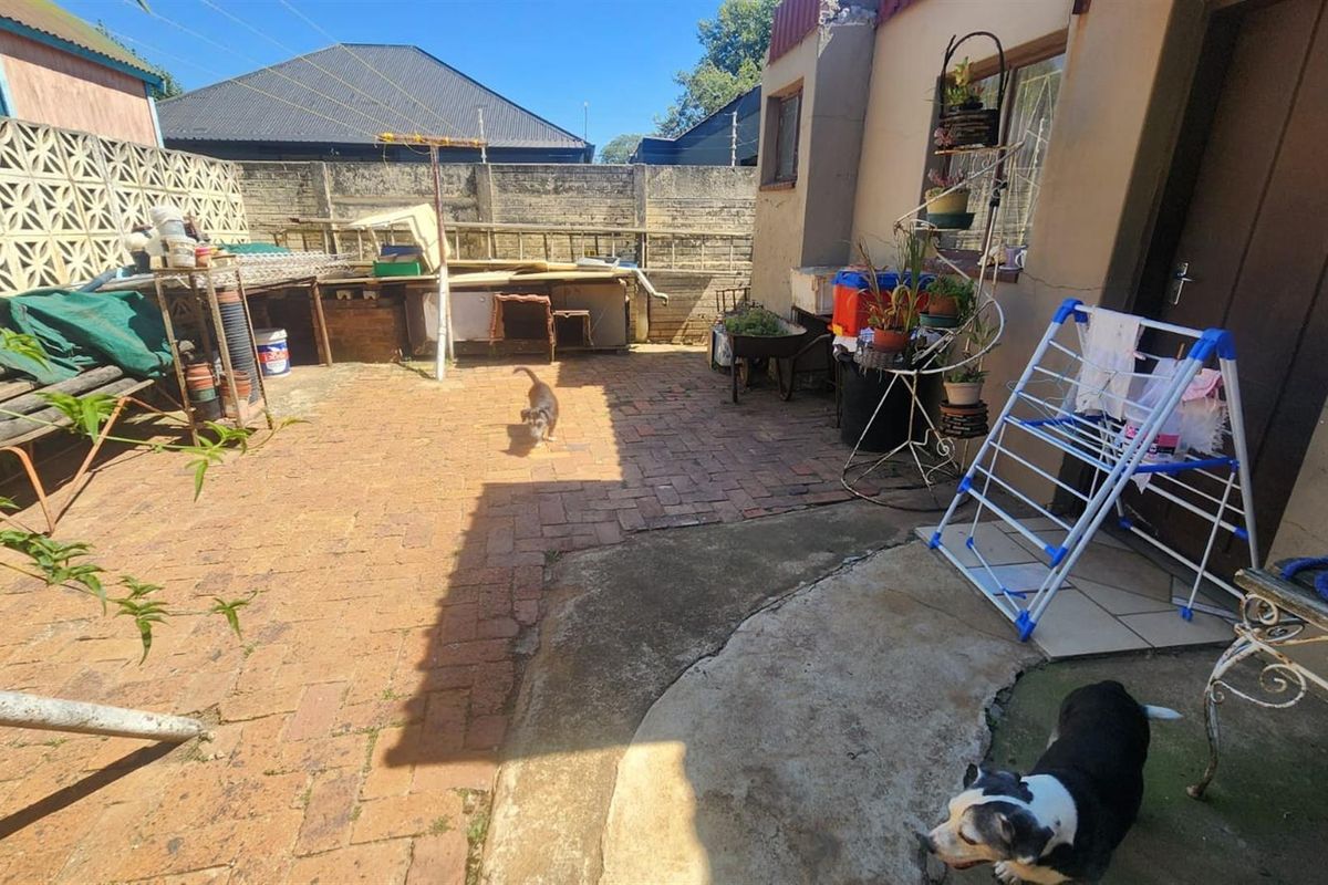 A rear courtyard area featuring brick and concrete paving, enclosed by a high boundary wall with decorative breeze blocks.