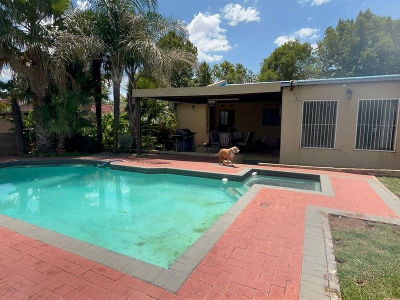Rear exterior view featuring a swimming pool with paved surround and a covered patio area, suitable for outdoor entertaining.
