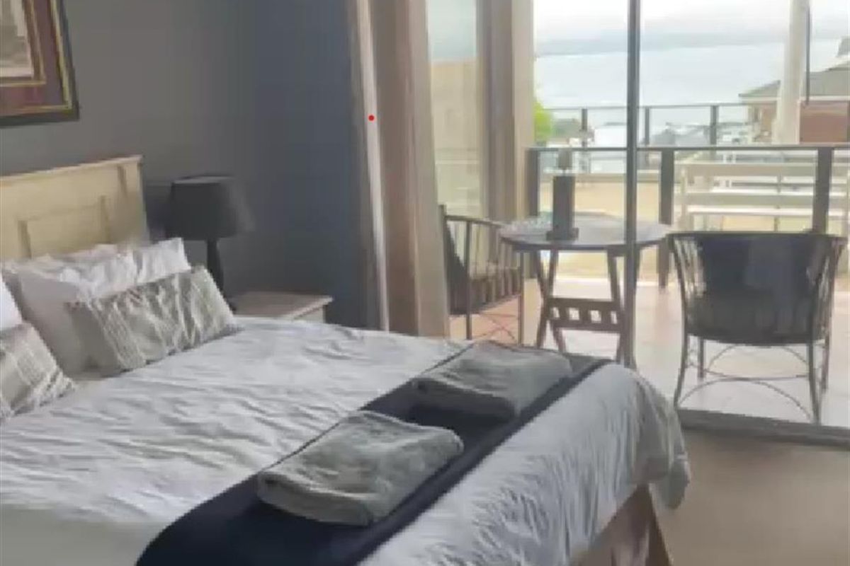 A bedroom featuring sliding glass doors that open onto a private balcony with scenic water views.
