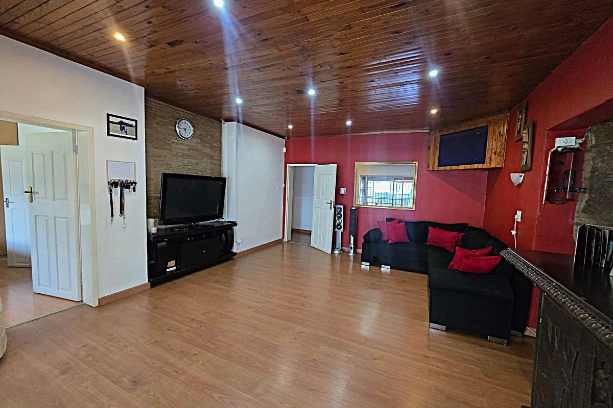 Spacious living room featuring a timber-clad ceiling, recessed downlighting, laminate flooring, and a textured stone feature wall.