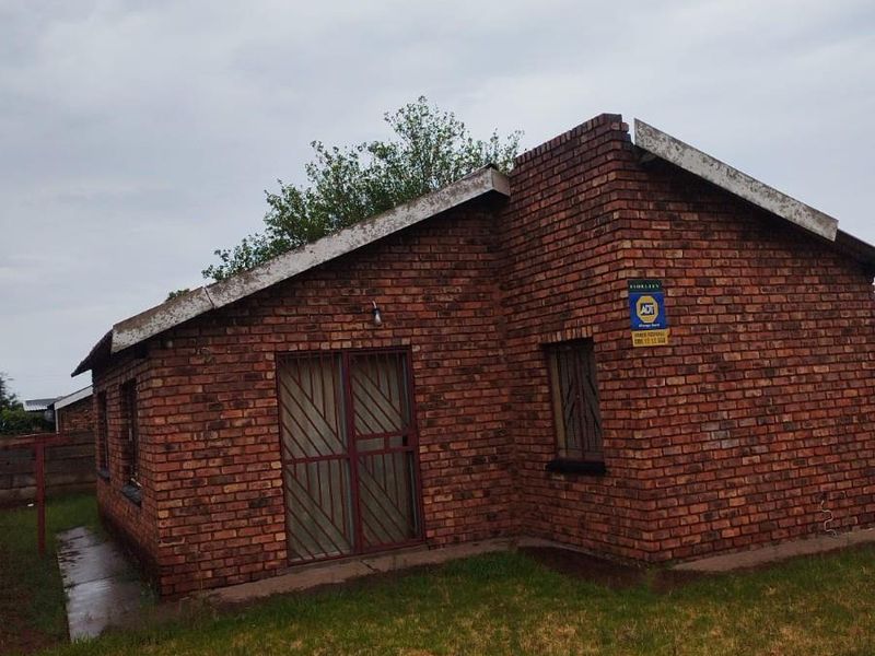 Exterior view of a face-brick house featuring security gates and a security system, set on a grassed plot.