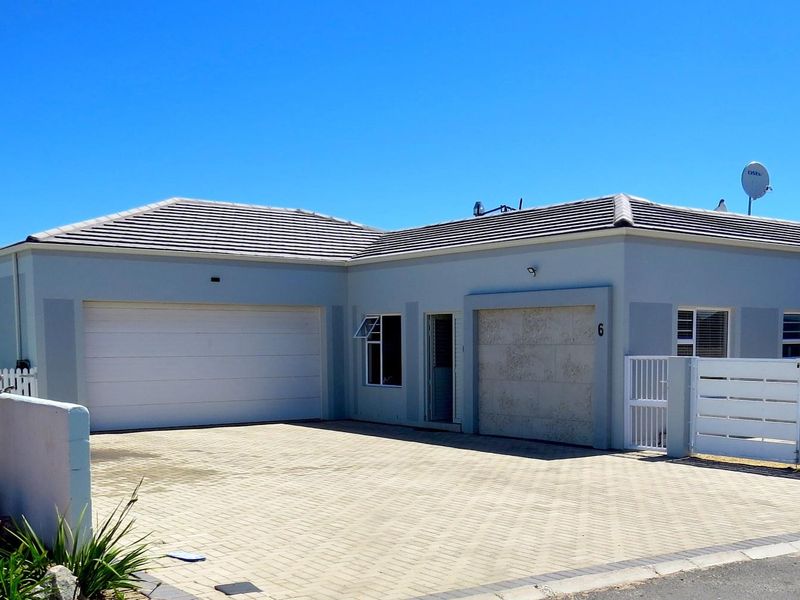 Front elevation of a single-story house featuring a double garage, paved driveway, and secure boundary walling.