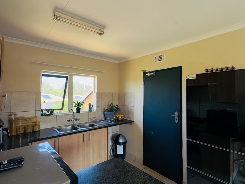 A functional kitchen featuring laminate cabinetry, granite countertops, a double basin sink, and tiled splashbacks, providing a practical workspace.