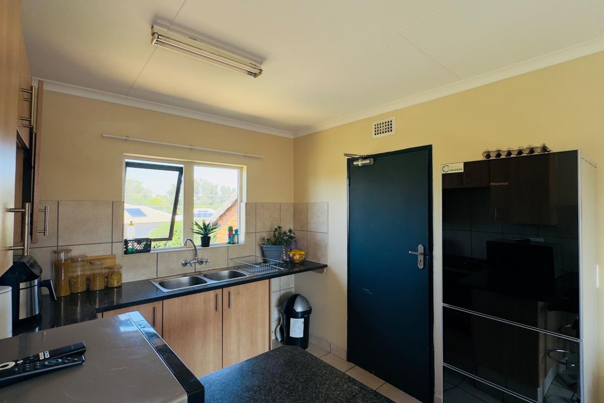 A functional kitchen featuring laminate cabinetry, granite countertops, a double basin sink, and tiled splashbacks, providing a practical workspace.