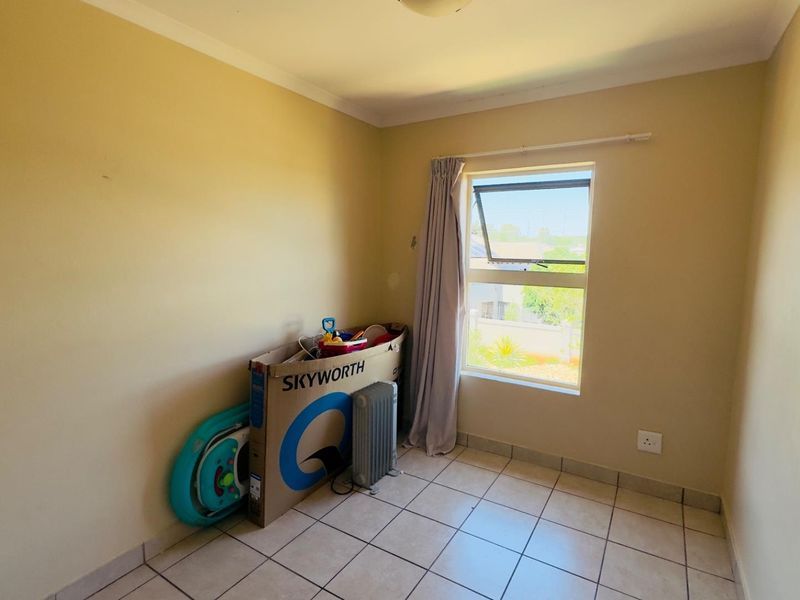 A compact bedroom featuring tiled flooring and a top-hung window, providing a functional space ready for personalization.