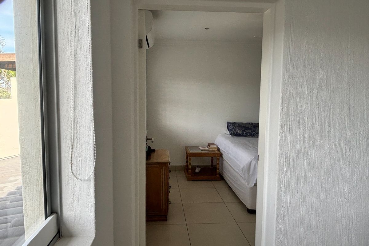 A view through a doorway into a bedroom featuring tiled flooring and a wall-mounted air conditioning unit.