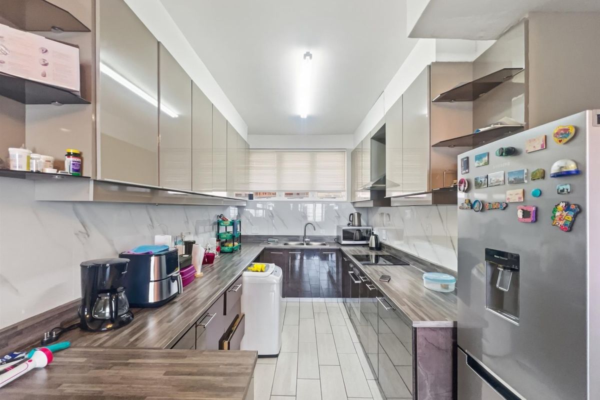 Modern galley-style kitchen featuring high-gloss cabinetry, marble-effect backsplash, wood-look laminate countertops, and integrated cooktop with extractor fan.