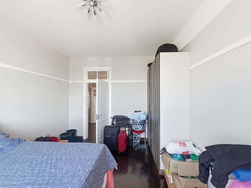 A bedroom featuring dark polished timber flooring, a built-in wardrobe, and a classic door frame with a transom window.