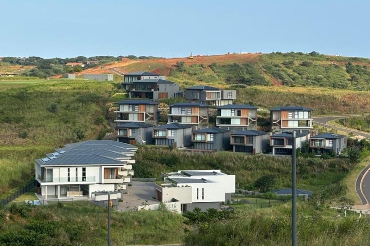 An elevated view of a modern residential townhouse estate featuring contemporary architectural designs set within a landscaped hillside environment.