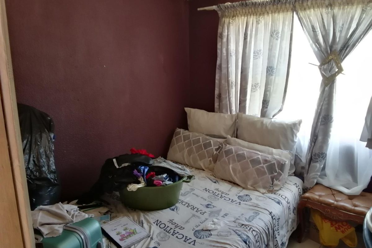 A bedroom featuring dark painted walls and a window with curtain rails. The room requires cosmetic updates to improve its overall condition.