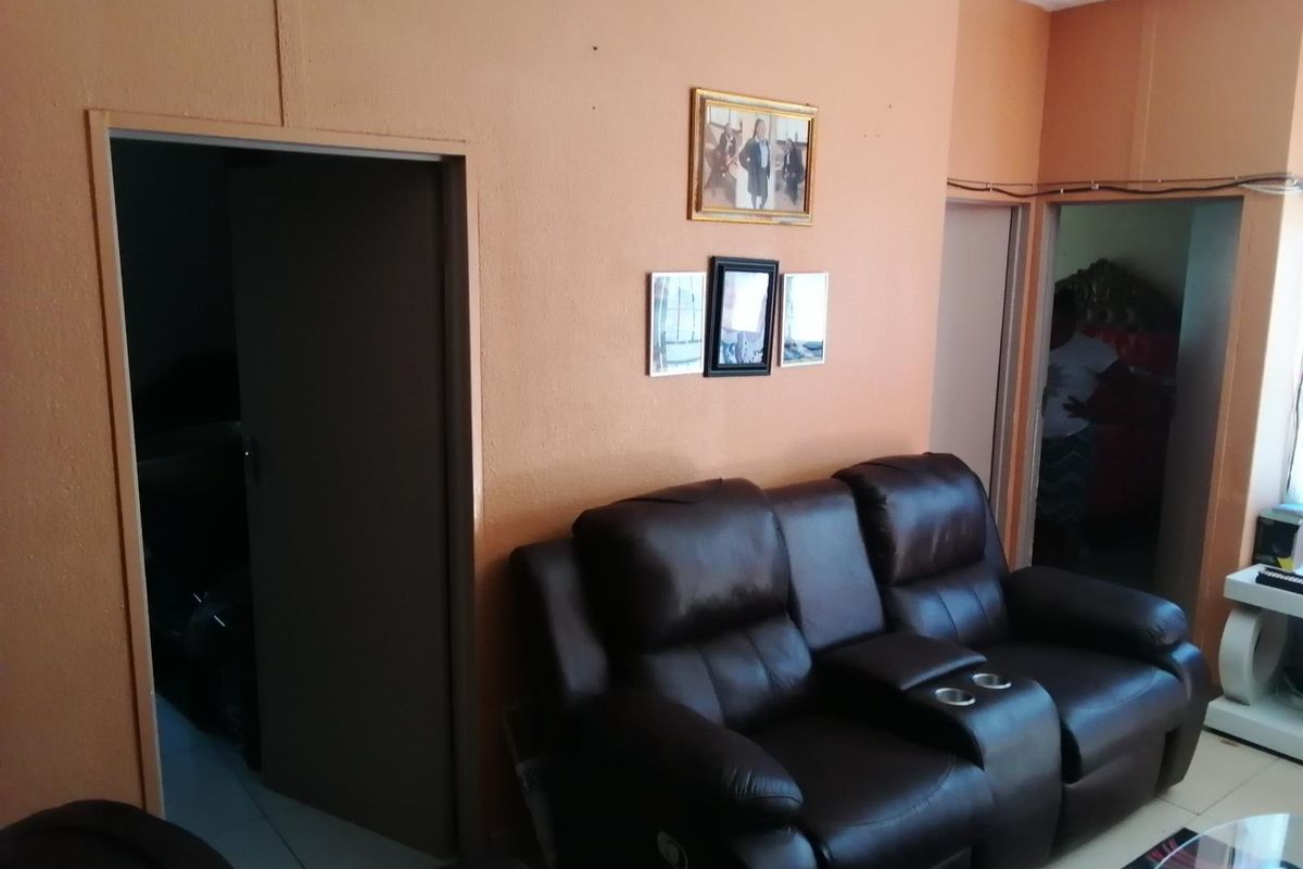 A living room area featuring tiled flooring and multiple internal doorways, currently showing signs of wear and exposed wiring.
