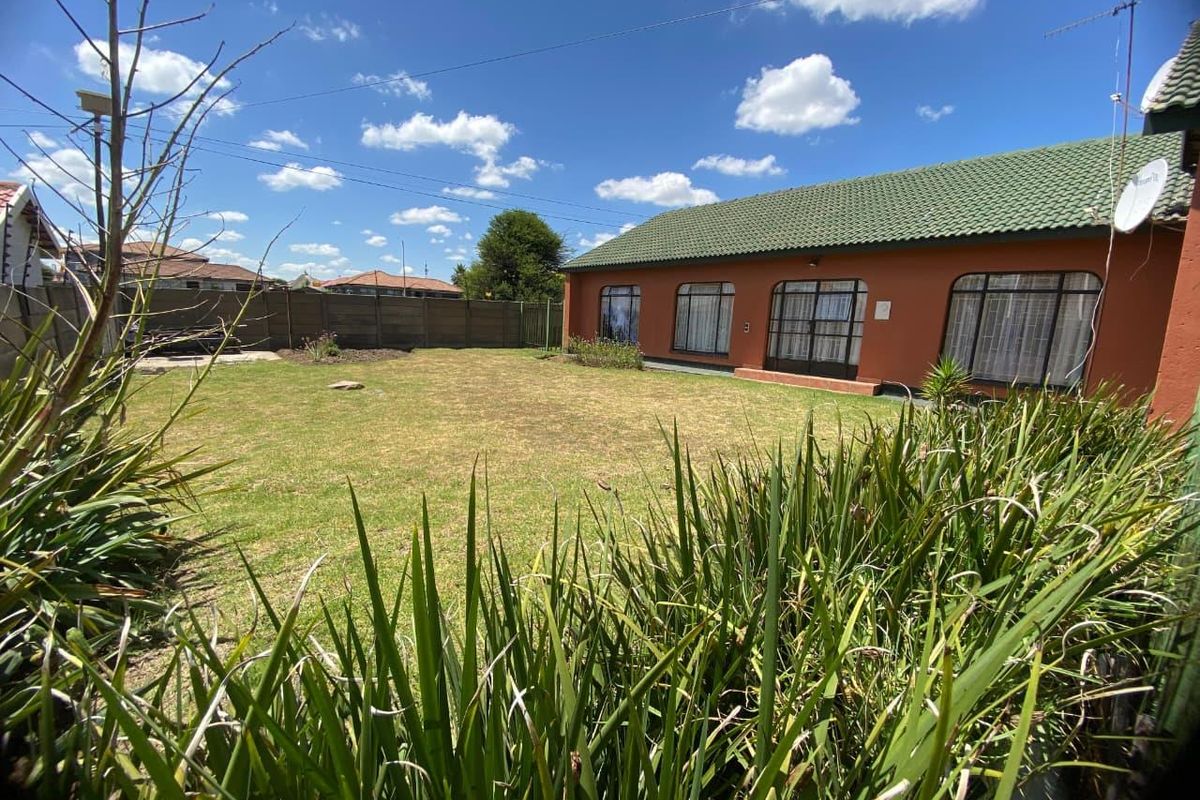 A spacious rear garden featuring a well-maintained lawn and a clear view of the property's rear elevation with large windows.