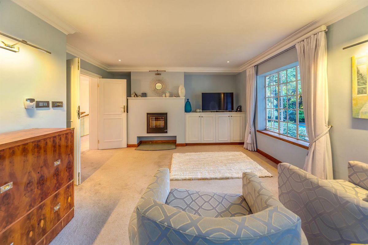 A comfortable living room featuring a built-in fireplace, custom cabinetry, and large windows that provide natural light and garden views.