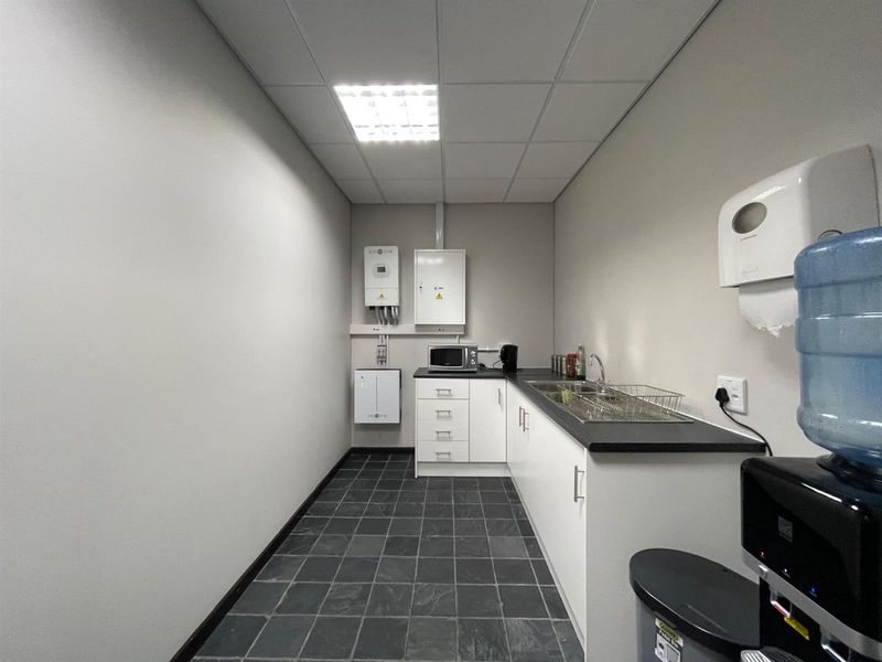 A functional office kitchenette featuring built-in cabinetry, a stainless steel sink, and integrated solar power infrastructure.