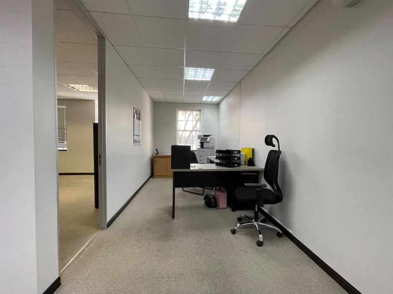 A functional office space featuring a suspended ceiling with recessed lighting and carpeted flooring, providing a clean and professional work environment.