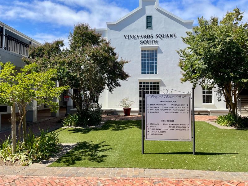 Front exterior view of Vineyards Square South office building, featuring a directory sign, manicured garden, and well-maintained white facade.