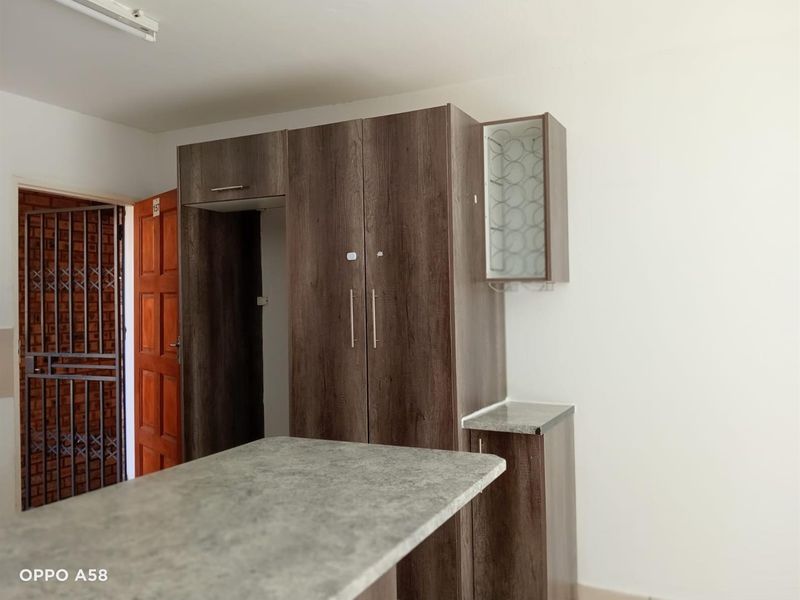 A compact kitchen area featuring modern wood-look built-in cabinetry, a stone-effect laminate countertop, and a functional breakfast bar.