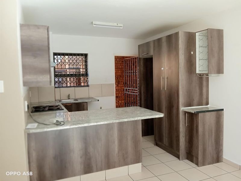 A functional kitchen featuring modern wood-look cabinetry, granite countertops, a built-in hob, and tiled flooring, offering a clean and practical workspace.