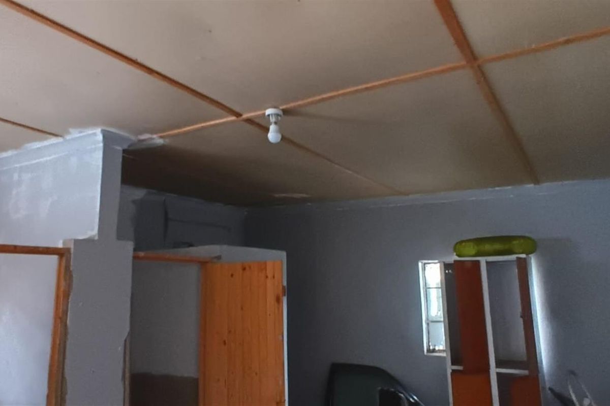 An interior room featuring a basic ceiling structure, painted walls, and wooden door frames, presenting a blank canvas for potential renovation.