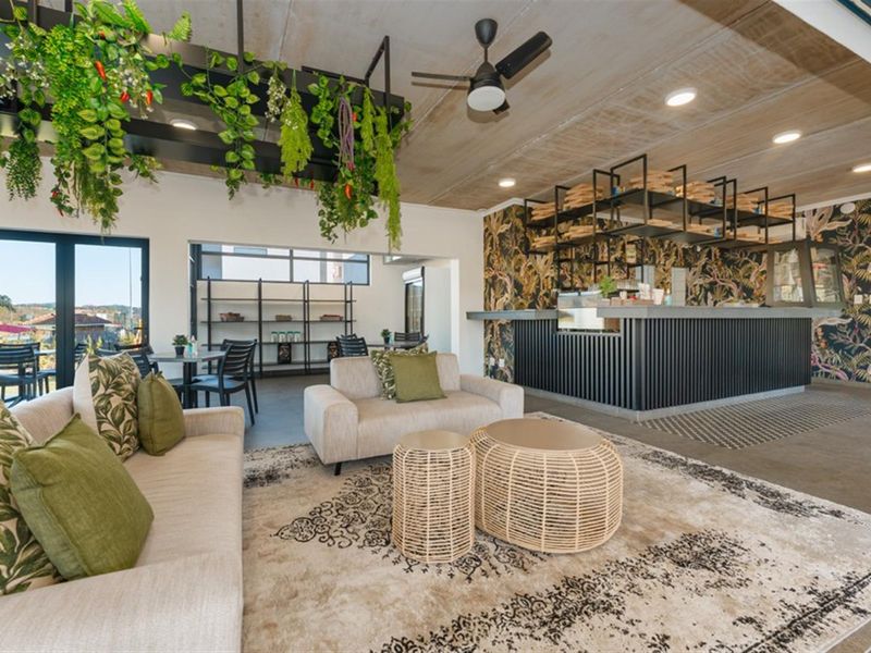 A modern open-plan living and bar area featuring a built-in service counter, industrial-style ceiling fan, and decorative wallpaper.