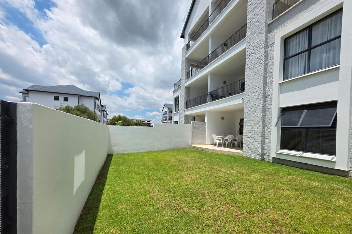 A ground floor apartment featuring a private garden, a covered patio, and multi-level balconies with modern brick and plaster facade finishes.