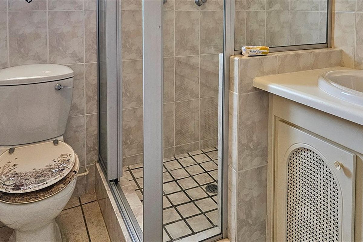 A compact bathroom featuring a tiled shower enclosure, a built-in vanity with a basin, and a standard toilet.