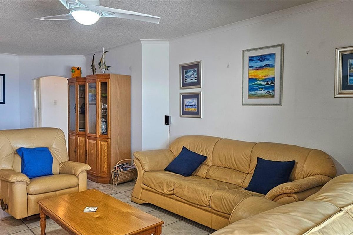 A spacious living room featuring tiled flooring and a ceiling fan, offering a comfortable and functional layout for relaxation.