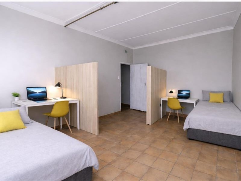 A shared bedroom featuring tiled flooring, two built-in room dividers creating separate study nooks, and neutral wall finishes.