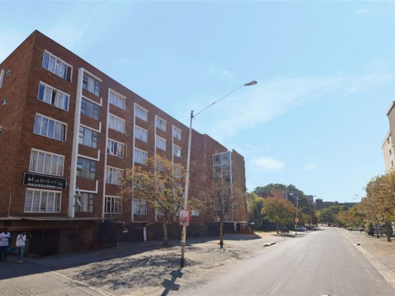 A street-level view of a multi-story brick apartment building, showcasing its exterior facade and surrounding urban environment.