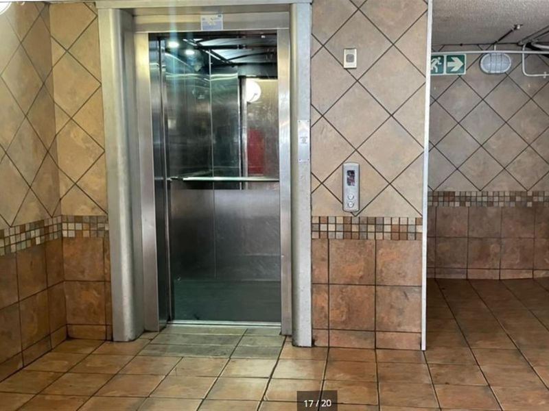 A functional apartment building elevator lobby featuring tiled walls and flooring, providing access to the lift.