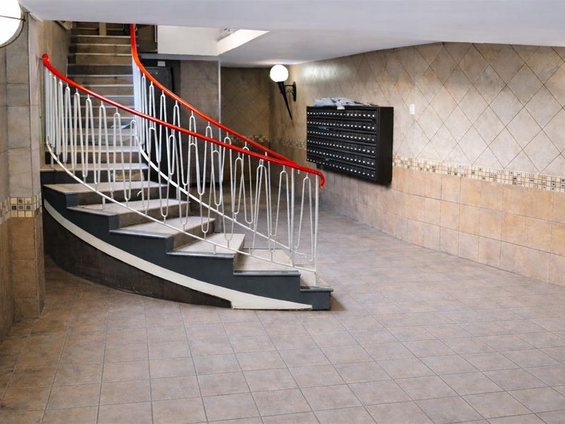 A communal apartment building entrance hall featuring a curved staircase with a metal balustrade and wall-mounted mailboxes.
