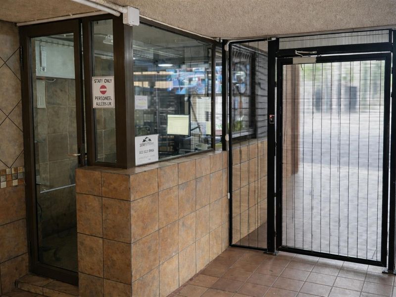 A secure building entrance or reception area featuring tiled walls, glass partitions, and a metal security gate.