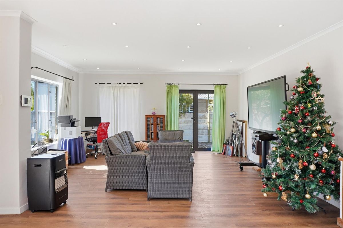 Spacious living room featuring recessed downlighting, wood-look flooring, and double glass doors providing direct access to the rear patio area.