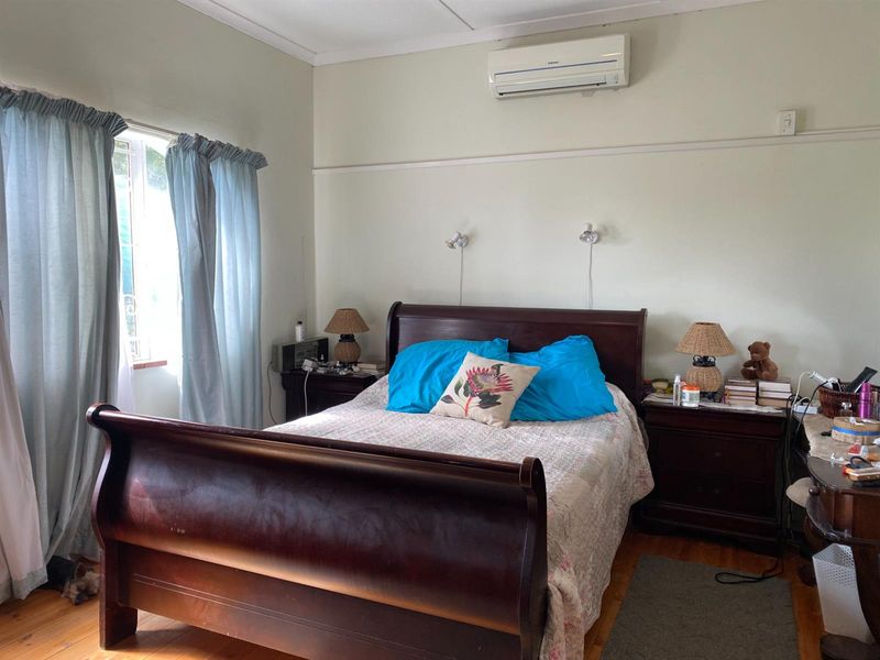 A bedroom featuring timber flooring, wall-mounted air conditioning unit, and dual wall-mounted reading lights.