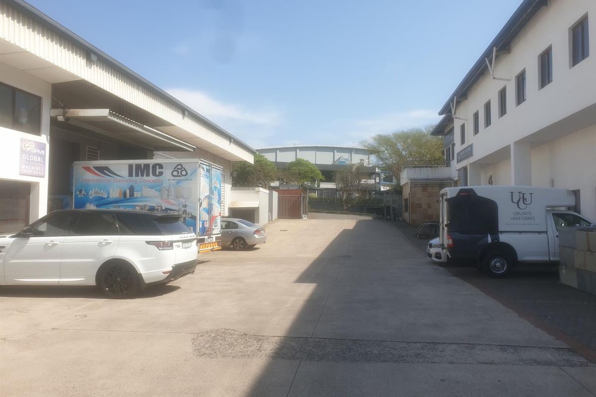 Industrial yard area featuring concrete paving between two warehouse buildings with access for delivery vehicles.