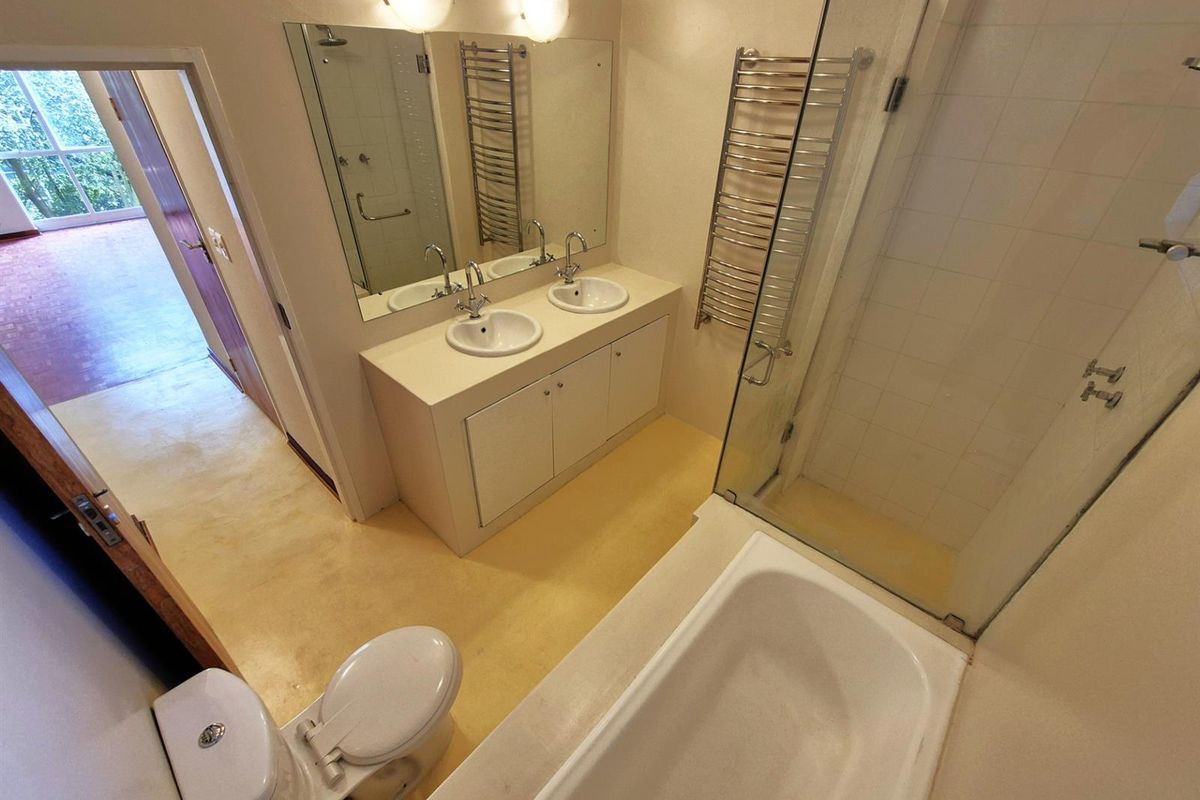 A functional bathroom featuring a double vanity, a glass-enclosed shower, a bathtub, and a wall-mounted heated towel rail.