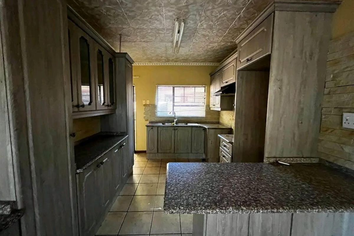 A dated kitchen featuring built-in cabinetry, granite countertops, and tiled flooring, offering a functional layout ready for modernization and cosmetic updates.