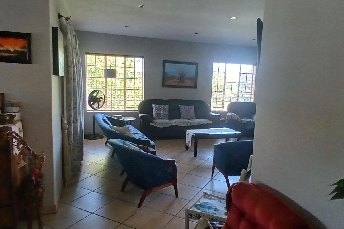 A spacious living room featuring tiled flooring, recessed ceiling lighting, and large windows that provide ample natural light.