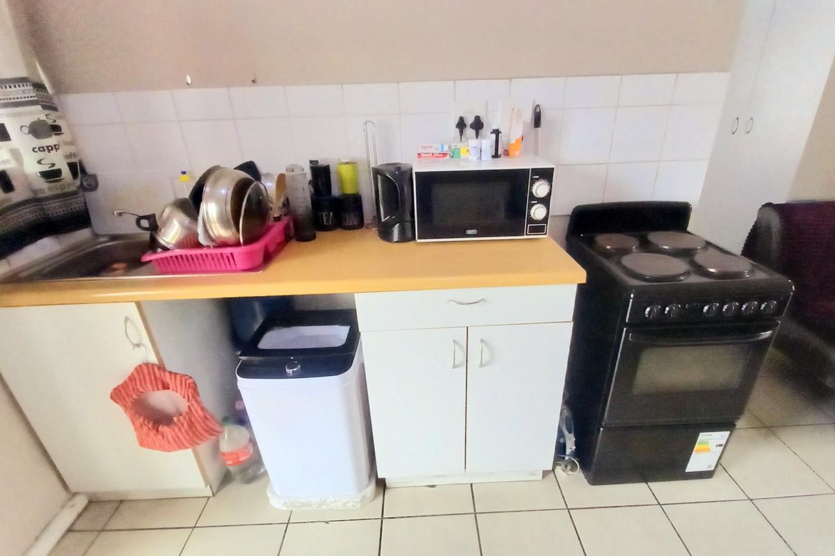 Compact kitchen area featuring white cabinetry, a laminate countertop, tiled splashback, and a freestanding electric stove.