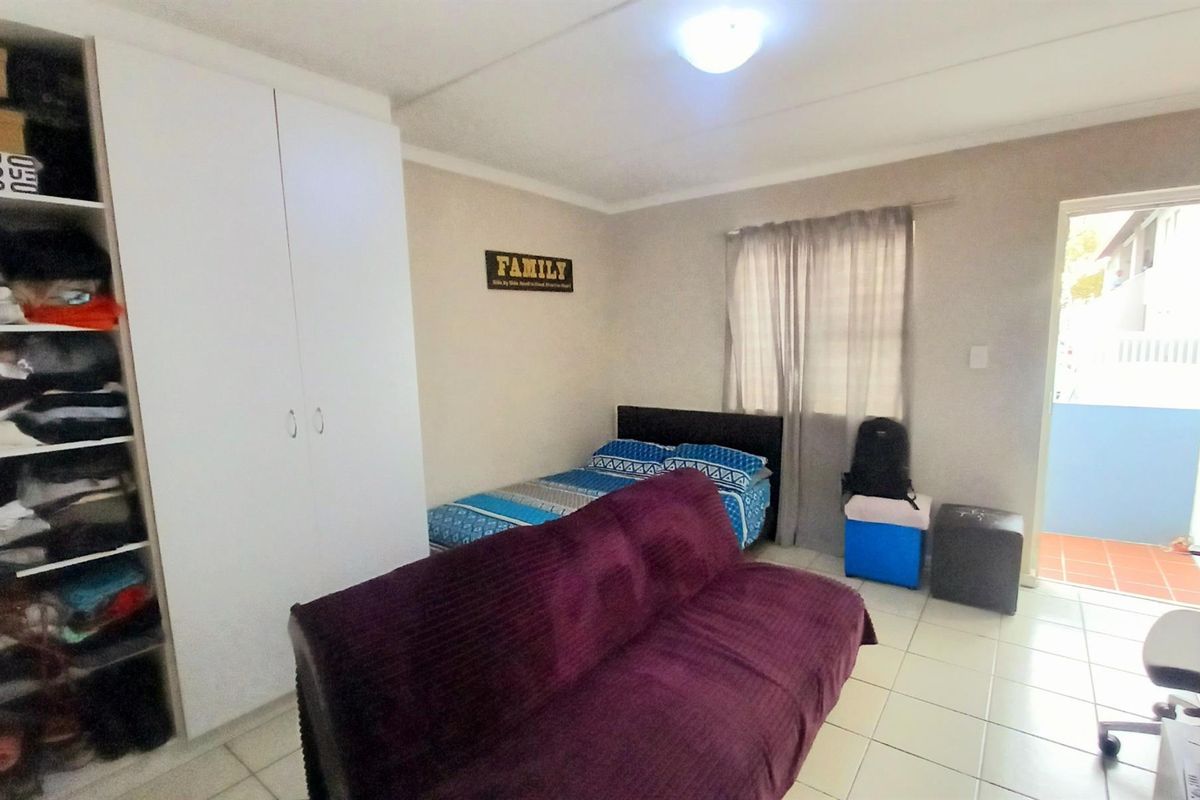 A bedroom featuring built-in cupboards, tiled flooring, and direct access to an outdoor balcony area.