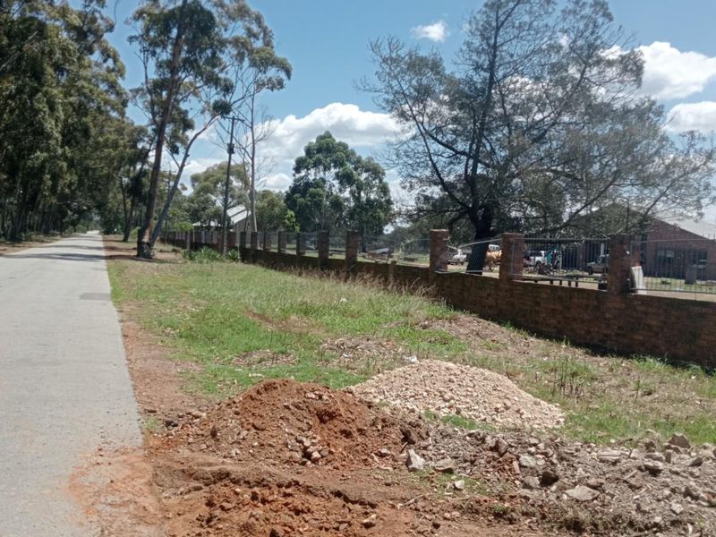 A street-level view of the property boundary featuring a brick perimeter wall and adjacent road access.
