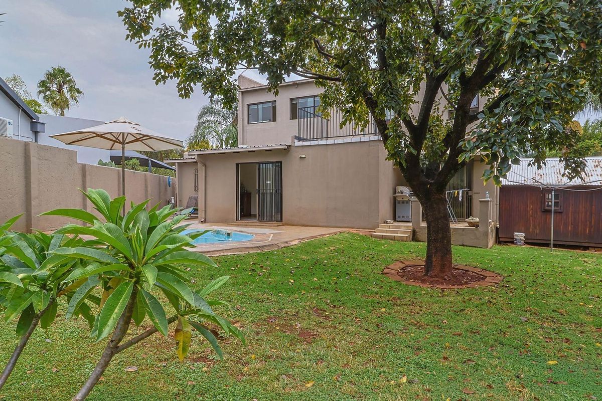Rear view of the house featuring a private garden, swimming pool, paved patio area, and a detached storage shed.