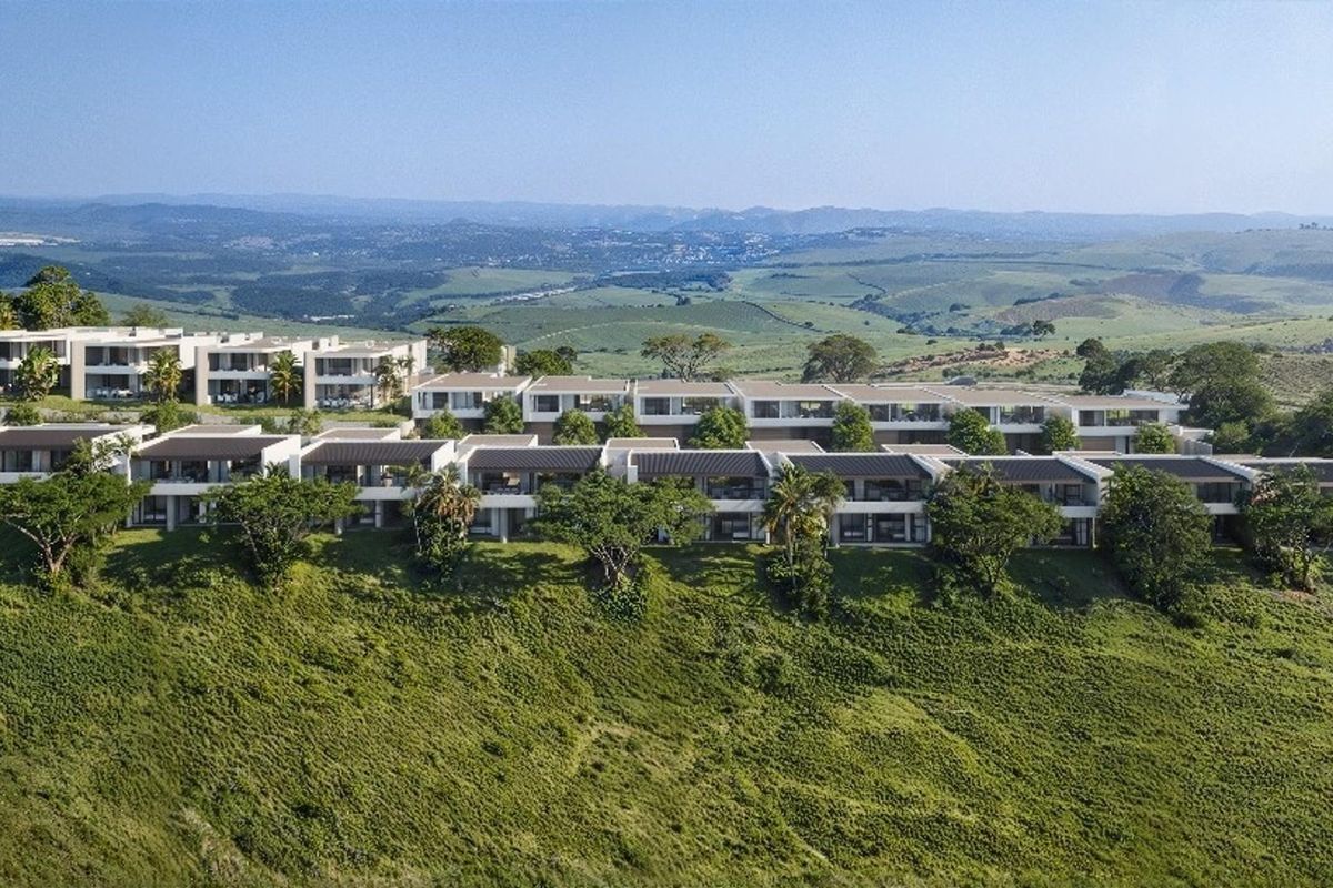 An aerial view of a modern residential estate complex situated on a hillside, showcasing contemporary architecture and expansive landscape views.