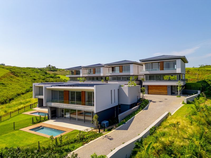 Aerial view of a modern multi-level residential complex featuring contemporary architecture, private swimming pools, paved driveways, and landscaped surroundings.